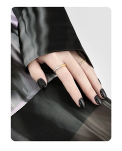 Close-up of minimalist gold and silver two-tone rings on a hand with black nails