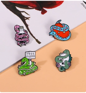 Macro shot of colorful snake enamel pins including skull, heart, and bottle designs