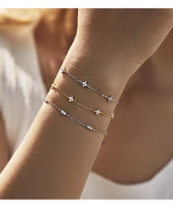 Close-up of three stacked S925 silver and gold clover bracelets with sparkling diamonds