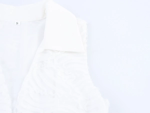Detailed close-up of white sleeveless dress with textured wave fabric and S size label