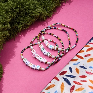 Detail of colorful beaded bracelets with LOVE and HAPPY letter beads and pearls