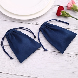Detail of dark blue velvet drawstring pouches on white wood background with carnations