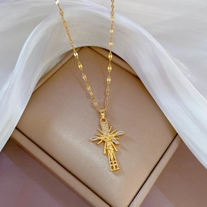 Golden crucifix necklace with Jesus figure and cubic zirconia stones on beige display stand