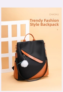 Close-up of waterproof black nylon backpack with orange leather trim and fur ball charm