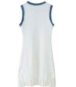 Detail of white knit dress featuring blue denim trim and elegant ruffled hemline