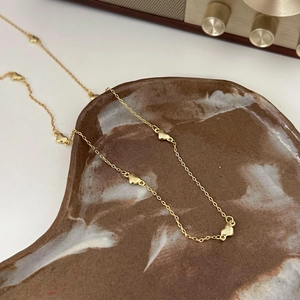 Minimalist gold 925 sterling silver necklace with tiny 3D heart pendants on a marble tray