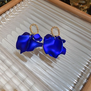Detailed macro view of matte blue petal earrings with gold textured rings and ear studs