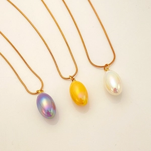 Detailed view of pear-shaped colorful drop pendants on gold snake chains in three colors