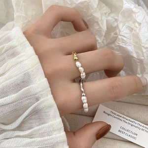 Anillos de perlas de agua dulce estilo francés en oro y plata mostrados en capas en la mano