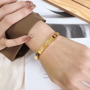 Polished gold titanium steel bangle featuring Forever engraving and heart pattern