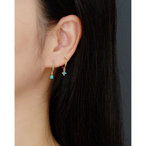 Detail of S925 silver hoop earrings with blue clover and teardrop gemstone charms