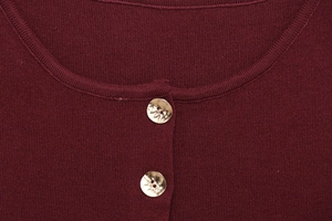 Détail du tissu en maille rouge foncé avec des boutons dorés texturés décoratifs