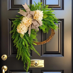 Pastoral hydrangea wreath with green leaves and burlap bow on a black farmhouse door