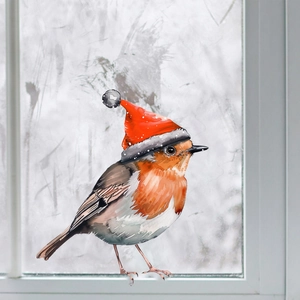 Close-up of a festive robin bird wearing a red Christmas hat against a winter window