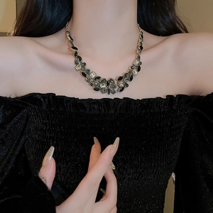 Close-up of luxury gold-tone water drop tassel necklace with emerald green crystals