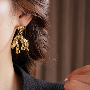 Macro detail of vintage golden leopard earring with black spots on a triangle dangle charm