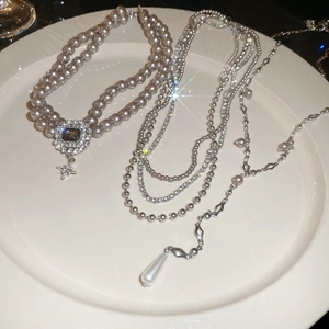 Detail of elegant layered pearl necklaces with crystal charms and a grey pearl pendant set