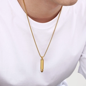 Close-up of a gold bullet pendant necklace on a male model with a box chain