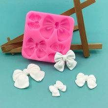 Pink silicone mold with bow-shaped cavities and finished white bow decorations