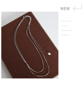 Detail of silver double-layered snake chain necklace with elegant white pearl pendant