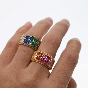 Golden rings set with rows of colorful rectangular zircons worn on fingers for wedding