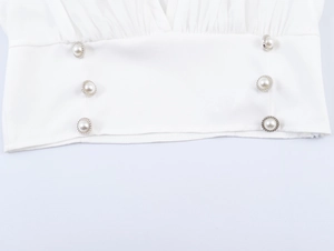 Détail d'une manche plissée blanche avec six boutons en perles nacrées à bord argenté