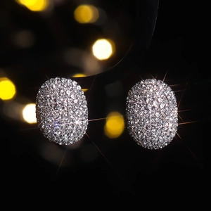 Élégantes boucles d'oreilles ovales argentées avec strass sur fond noir luxueux