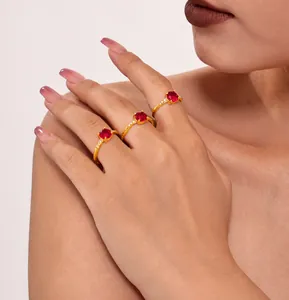 Detailed view of three luxury gold-plated rings with oval red zircon stones on model fingers