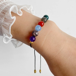 Detail eines verstellbaren Regenbogenstein-Perlenarmbands mit schwarzer Kordel und Gold