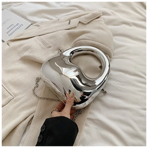 Close-up of a silver mirror acrylic evening bag with hollow handle on a beige blazer
