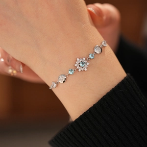 Detailed view of silver flower bracelet with blue gemstones and white zircons on a wrist