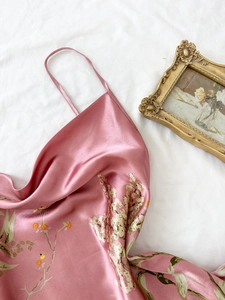 Canotta in raso rosa con stampa floreale francese distesa su uno sfondo di tessuto bianco