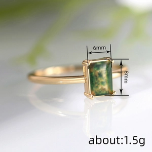 Elegant gold-tone rectangle ring with 6x8mm green stone inlay on reflective surface