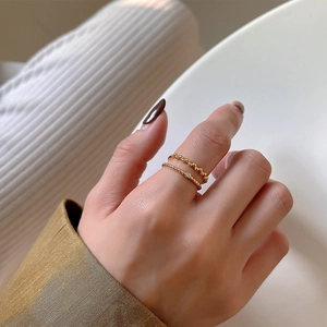 Close-up of minimalist beaded gold rings with zircon stones worn by a model