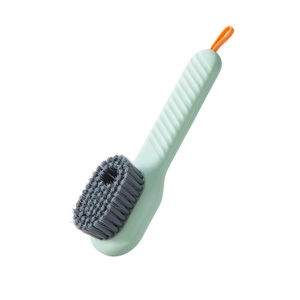 Multi-functional soft bristle shoe brush with green handle and orange silicone hanging loop.
