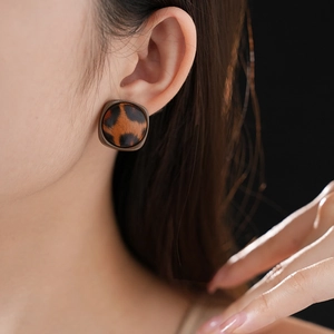 Gros plan de boucles d'oreilles carrées imprimé léopard en similicuir porté