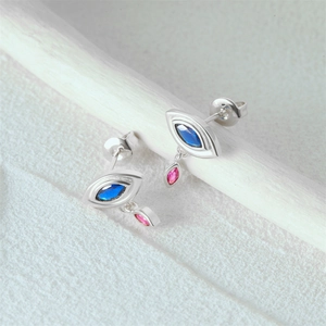 Macro detail of silver evil eye earring featuring blue marquise and pink drop gemstones