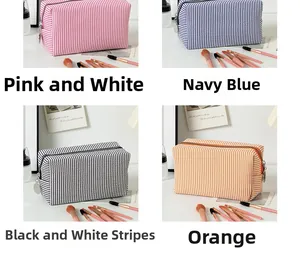 Detailansicht der Seersucker-Kosmetiktaschen in Rosa, Marine, Schwarz und Orange gestreift