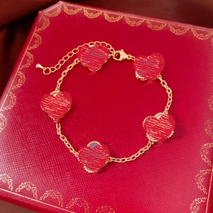 Gros plan d'un bracelet plaqué or 18 carats avec cinq cœurs rouges dans un écrin rouge