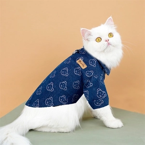 Detailed view of blue denim pet shirt with bear prints and leather smile tag on a cat