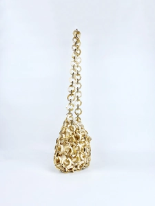 Detail of cream acrylic hexagonal plates and gold rings woven into a shoulder bag