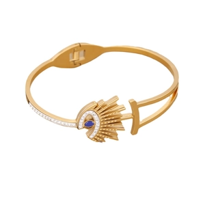Polished gold Evil Eye bangle featuring a blue gemstone and sparkling crystals in white background