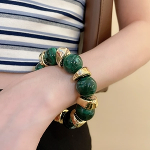 Detail of beaded bracelet with green marble resin beads and golden geometric spacers