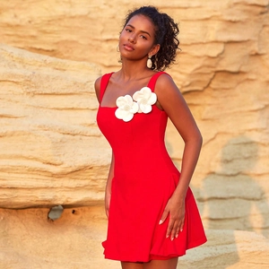 Détail d'une robe courte rouge avec fleurs 3D blanches et texture de tissu raffinée