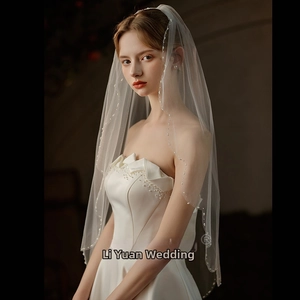 Detailed view of handmade ivory pearls on a single-layer bridal veil with metal comb
