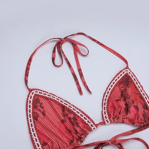 Détail d'un haut de bikini rouge à fleurs avec bordures en crochet blanc et licou