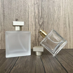 Detail view of frosted and clear glass square perfume spray bottles on a wood texture