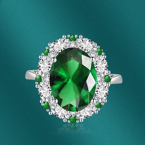 Macro shot of silver ring featuring a large oval green gemstone and diamond halo crystals