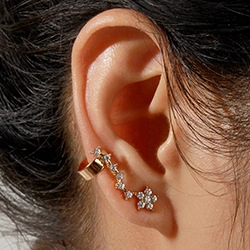 Detail of flower-shaped gold ear cuff with sparkling rhinestones and pearl accents