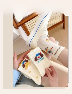 Detail of cream cotton socks featuring cute cartoon puppies and yellow star patterns